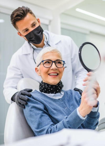Woman and dentist looking at smile in dental care
