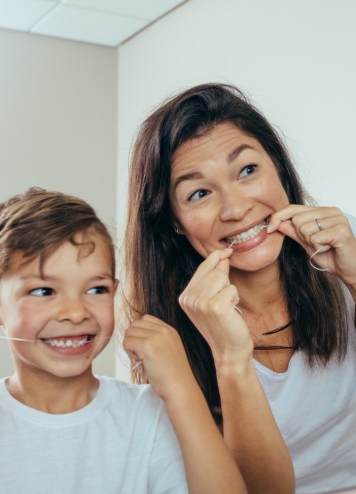 Mother and son flossing teeth to prevent dental emergencies
