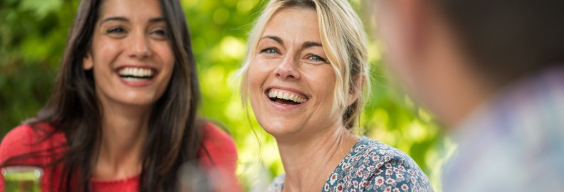 Two women smiling after replacing missing teeth